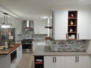 A modern kitchen with white cabinets, a stone tile backsplash, stainless steel appliances, and a central island with a wine rack.